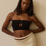 Woman wearing a black strapless system against a plain background