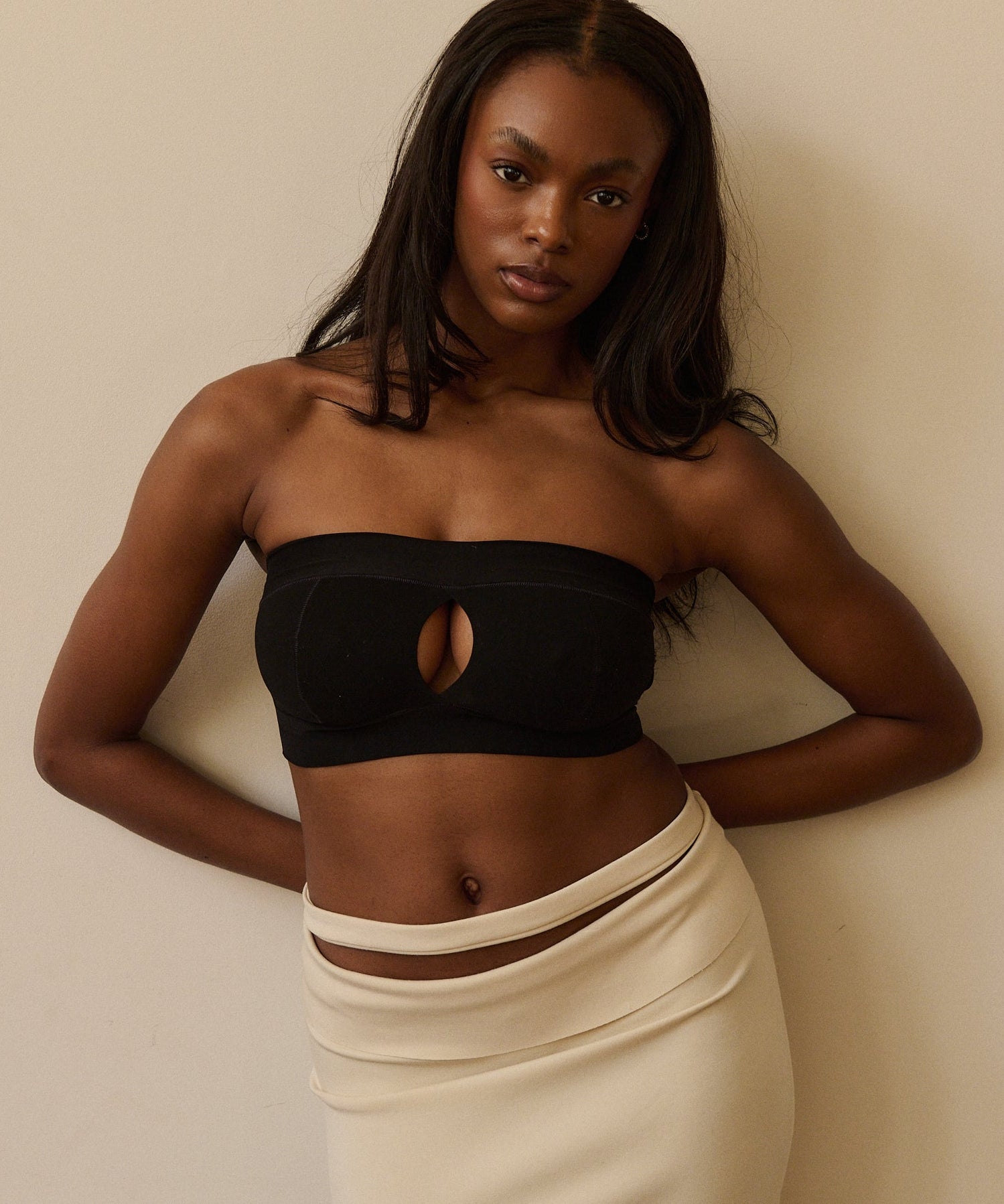 Woman wearing a black strapless system against a plain background