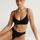 Person wearing a black cami system against a plain background