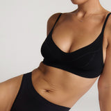 Person wearing a black cami system against a plain background