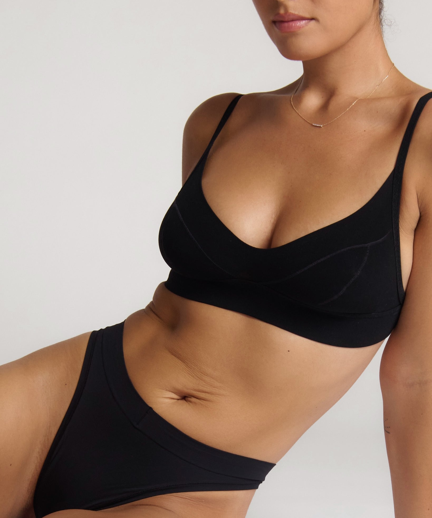 Person wearing a black cami system against a plain background