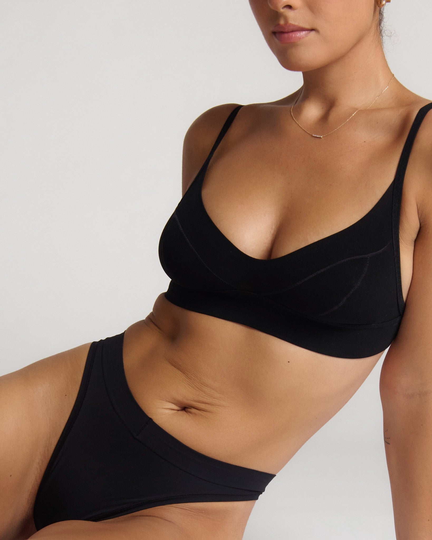 Person wearing a black cami system against a plain background