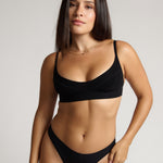 Person wearing a black cami system against a plain background