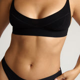 Person wearing a black cami system against a plain background