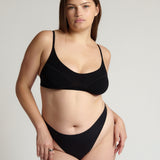 Person wearing a black cami system against a plain background