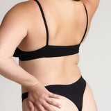 Person wearing a black cami system against a plain background