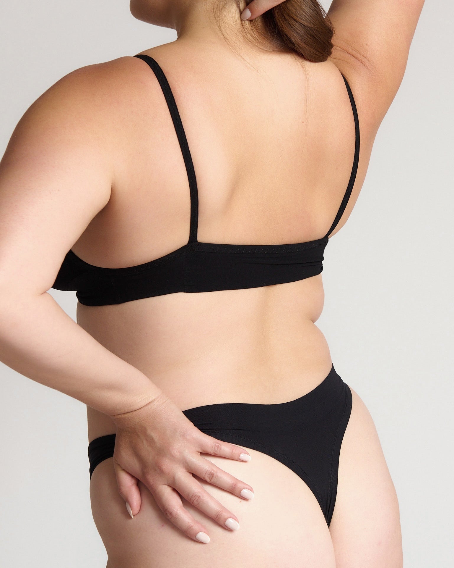 Person wearing a black cami system against a plain background