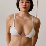  woman wearing a minimal triangle in cloud against a plain background