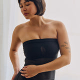 Woman wearing a black sheer dress against a plain background