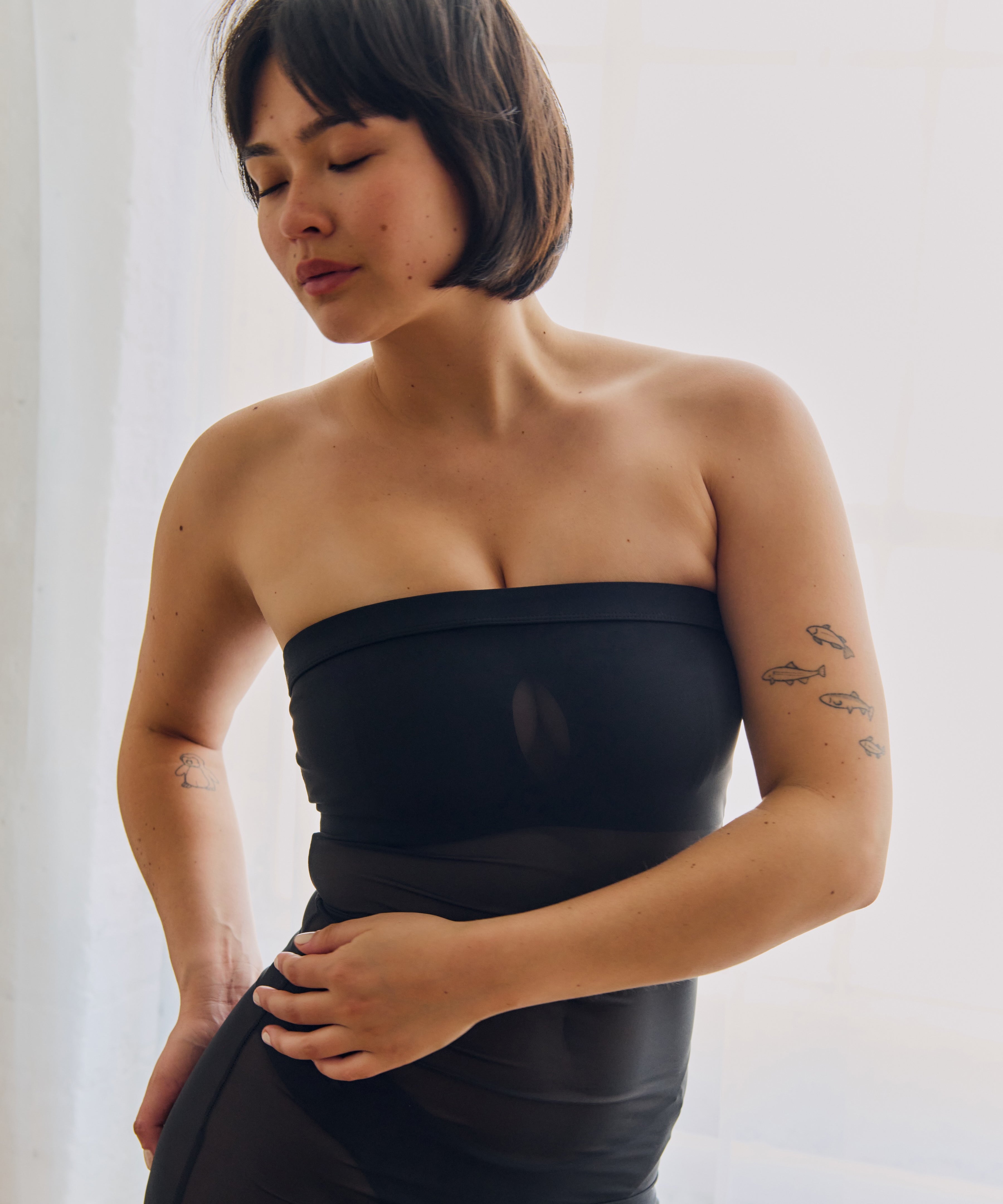 Woman wearing a black sheer dress against a plain background