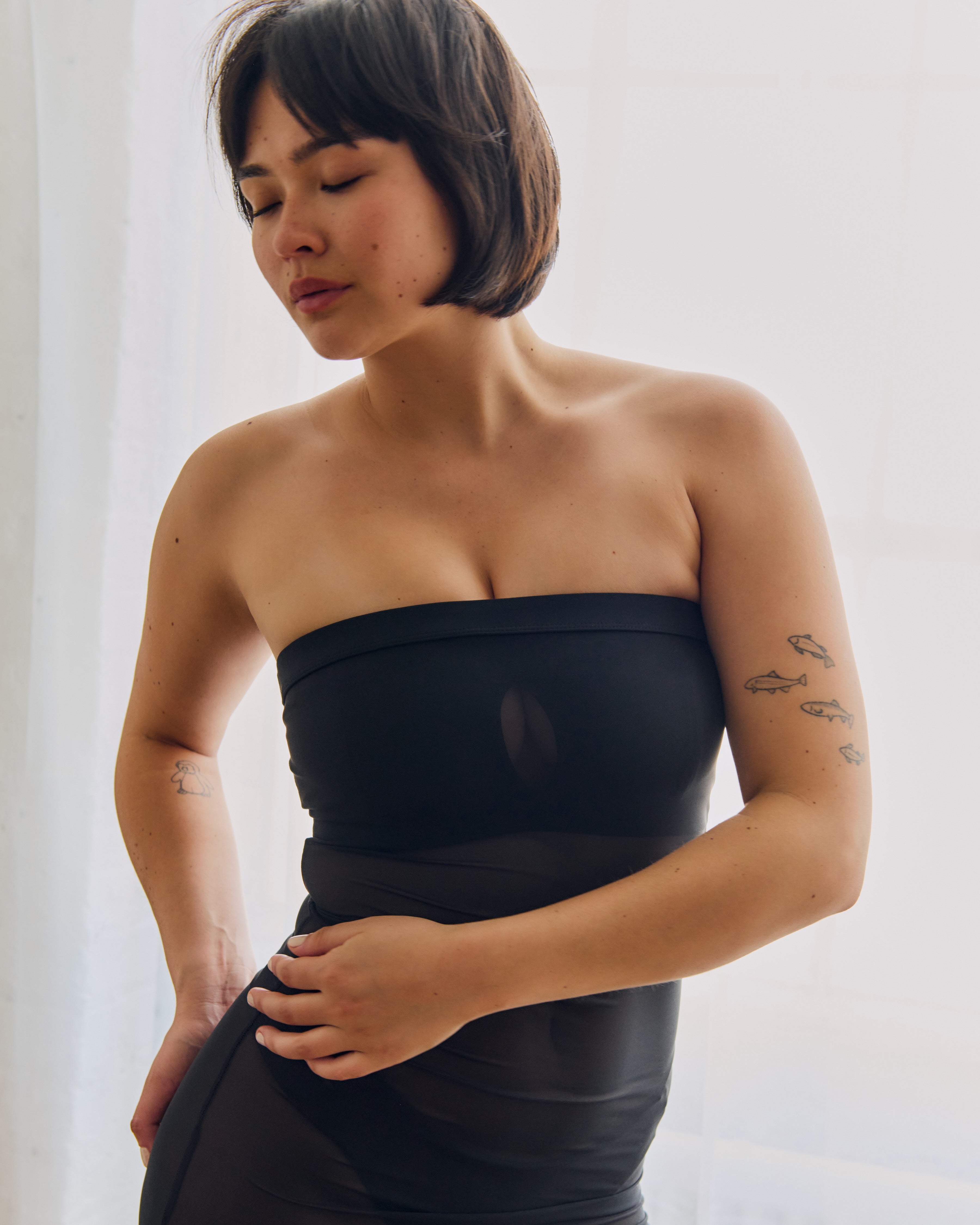 Woman wearing a black sheer dress against a plain background