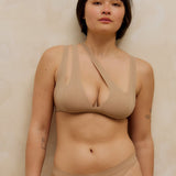 Woman wearing a light tee system and matching thong against a plain background.