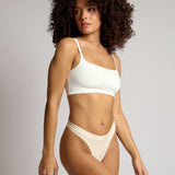 Woman wearing a white cropped cami on a plain background