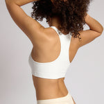 Woman wearing a white racerback on a plain background
