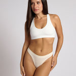 Woman wearing a white racerback on a plain background