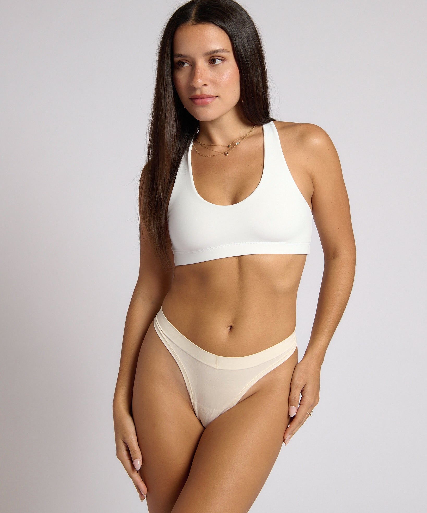 Woman wearing a white racerback on a plain background