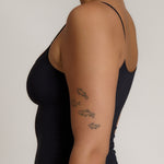 Woman wearing a cami top against a plain background