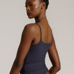 A woman modeling a myst cami and a matching thong against a plain light gray studio background.