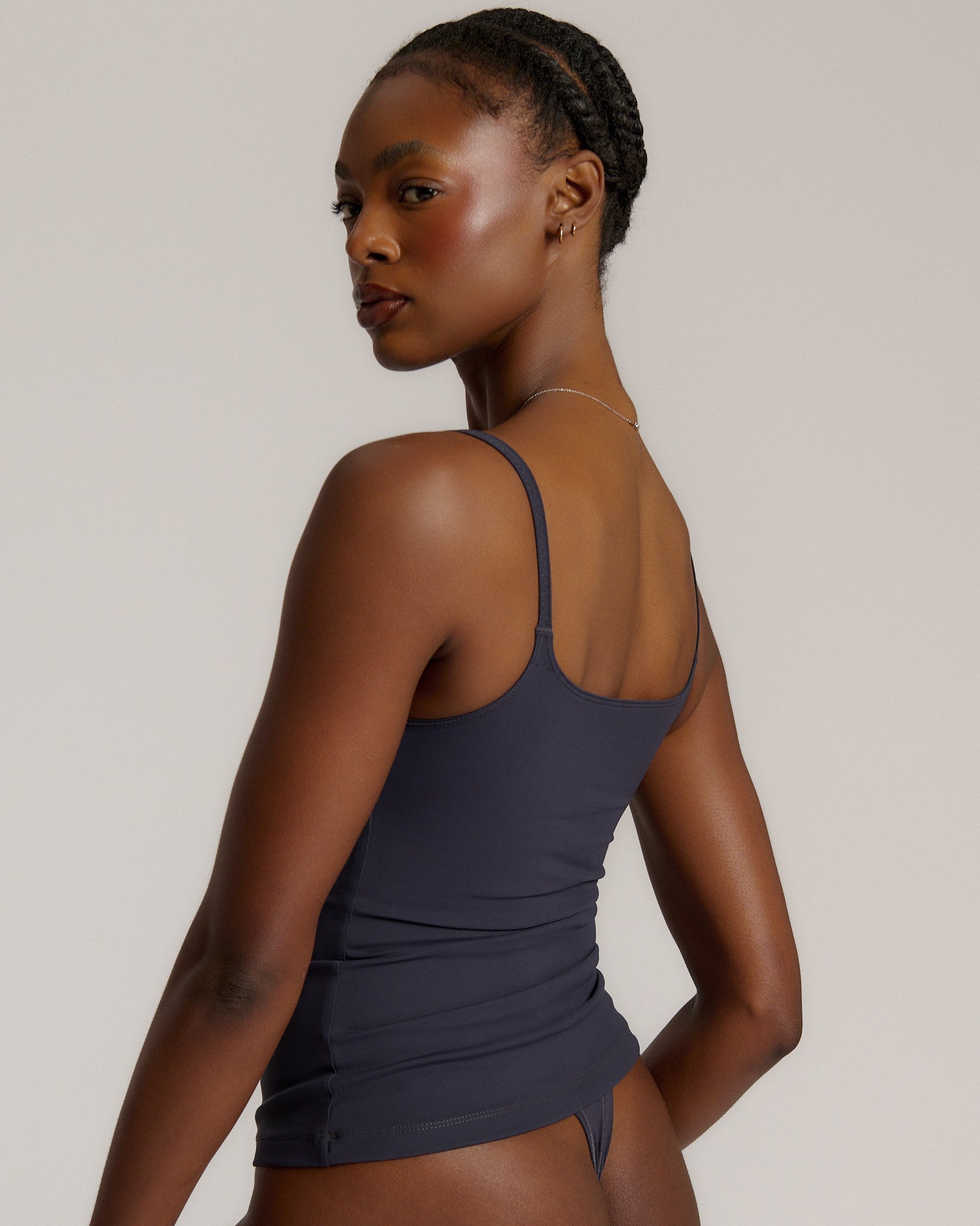 A woman modeling a myst cami and a matching thong against a plain light gray studio background.