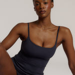A woman modeling a myst cami and a matching thong against a plain light gray studio background.