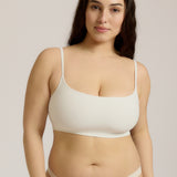 Woman wearing a white bra and white underwear on a plain background