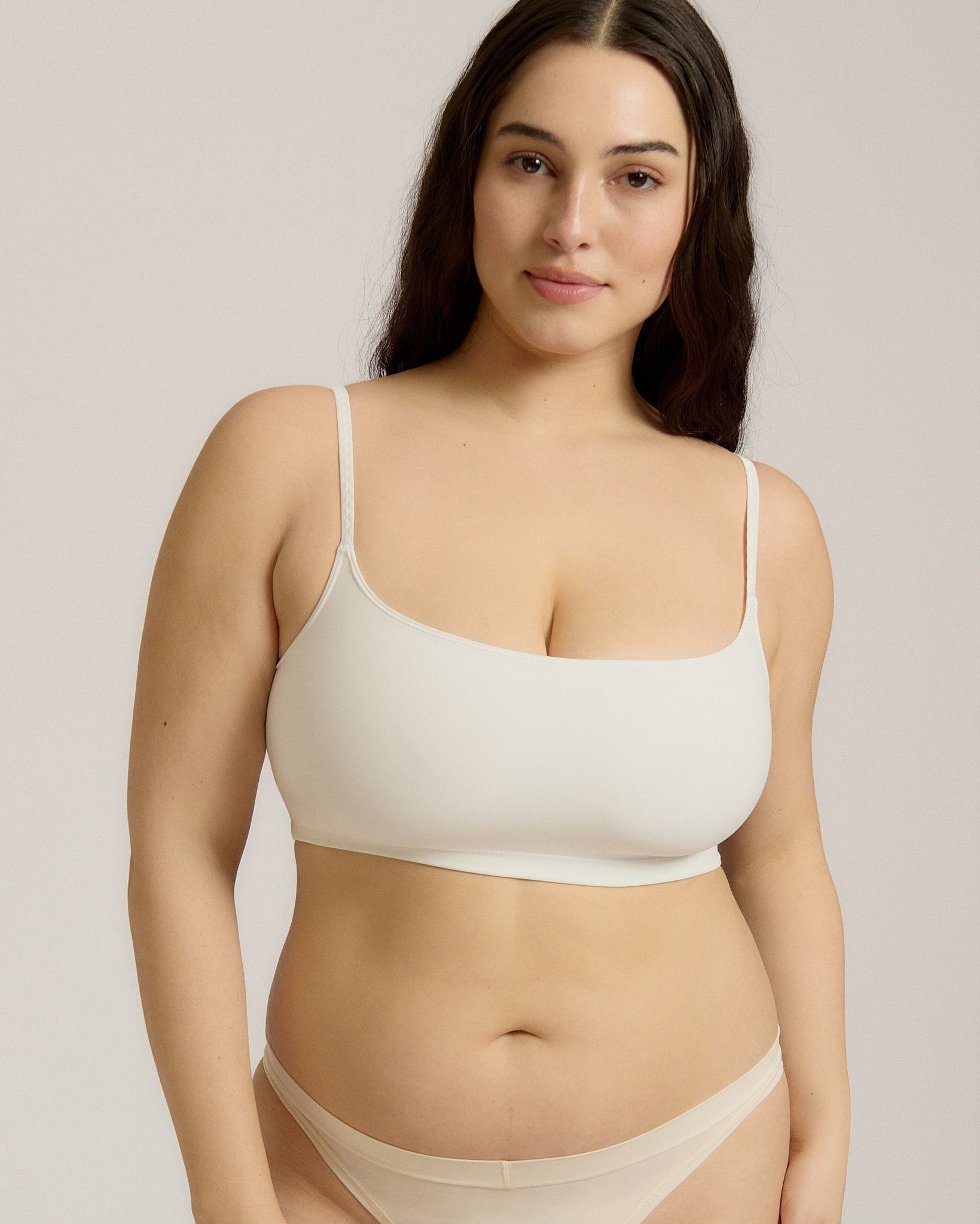 Woman wearing a white bra and white underwear on a plain background