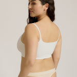 Woman wearing a white bra and white underwear on a plain background