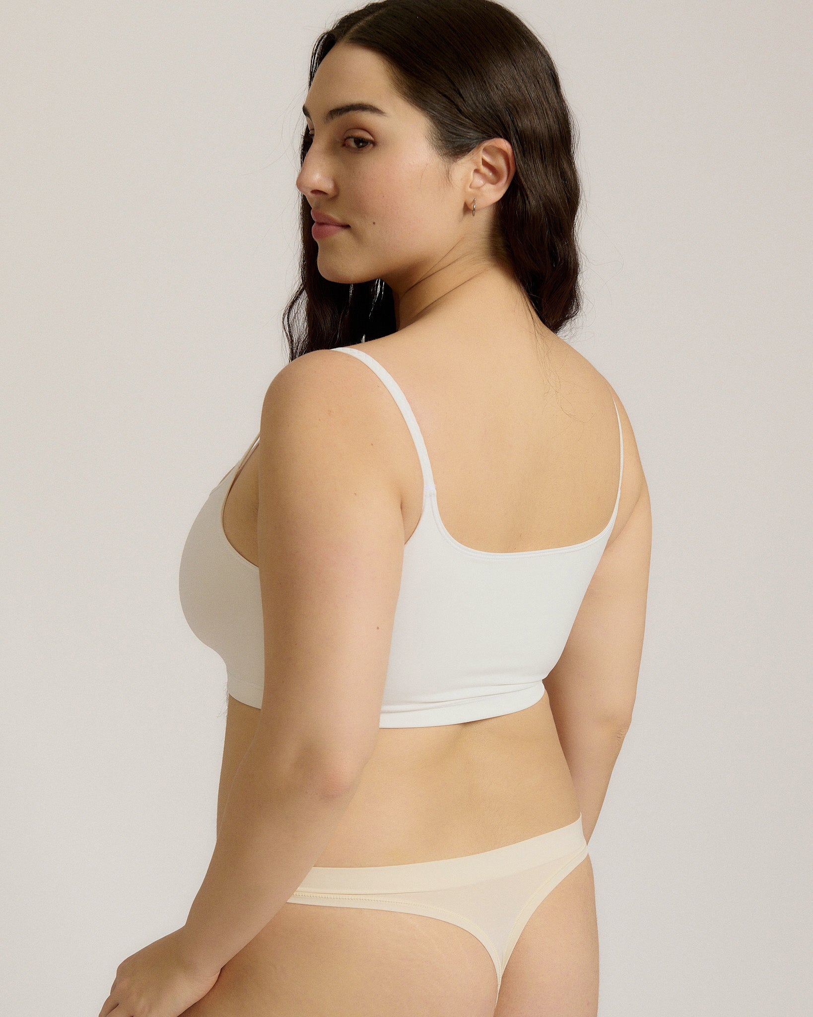 Woman wearing a white bra and white underwear on a plain background