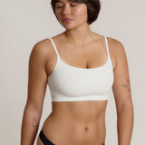 Woman wearing a white bra and white underwear on a plain background