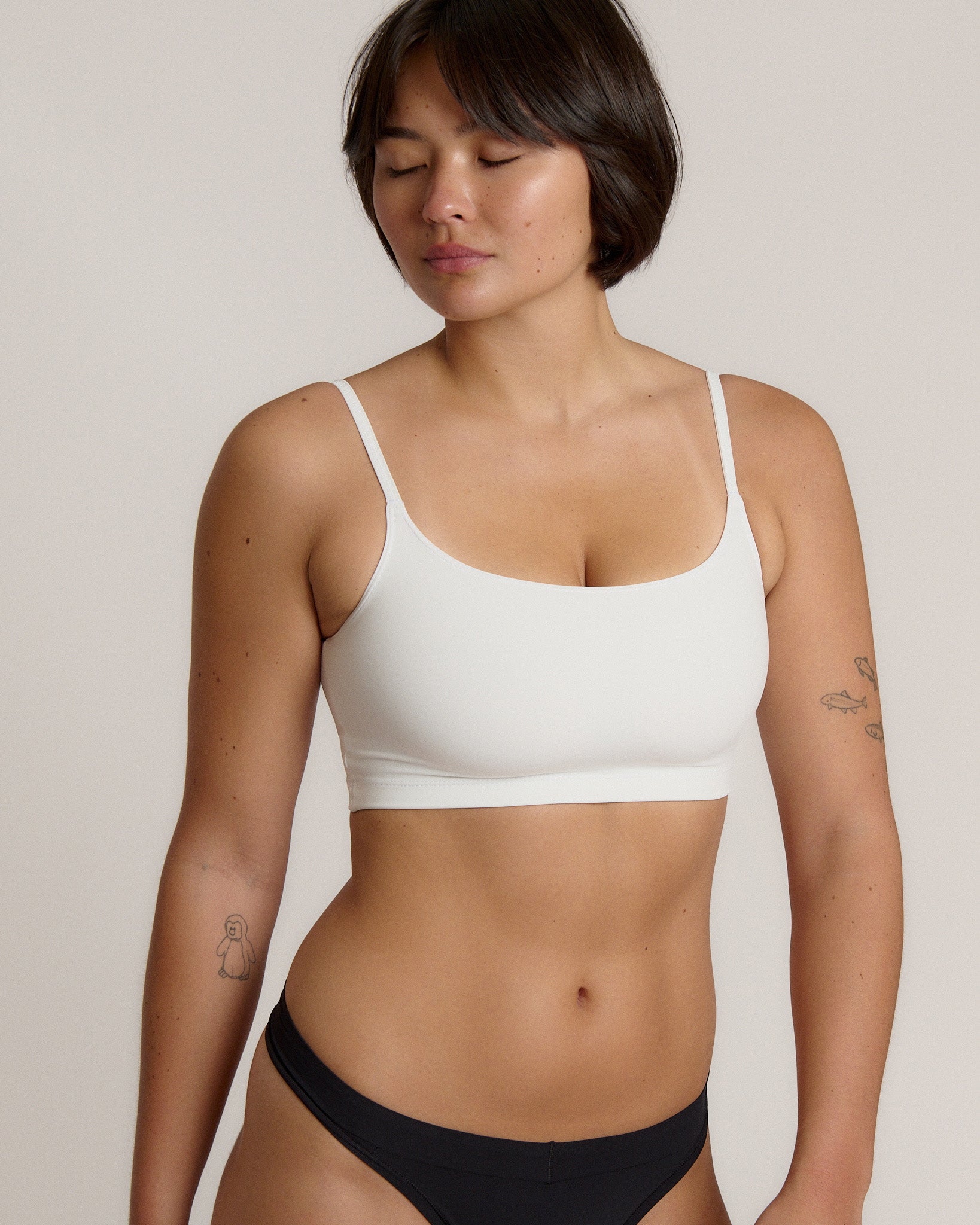 Woman wearing a white bra and white underwear on a plain background