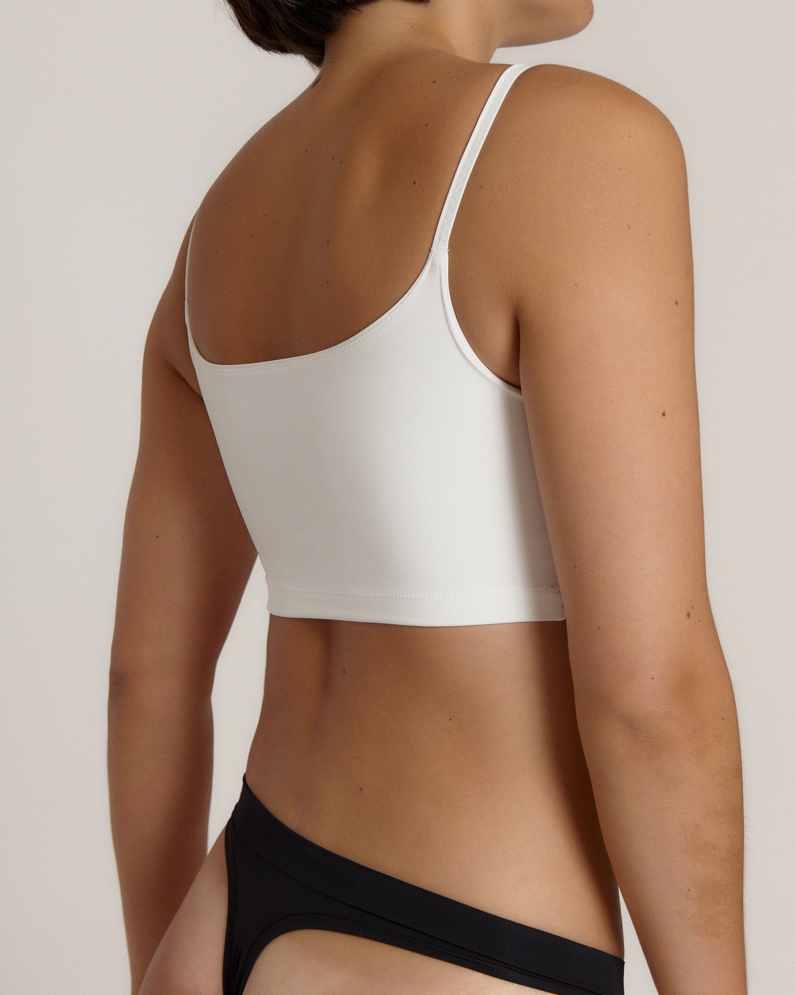Woman wearing a white bra and white underwear on a plain background