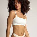 Woman wearing a white cropped cami on a plain background