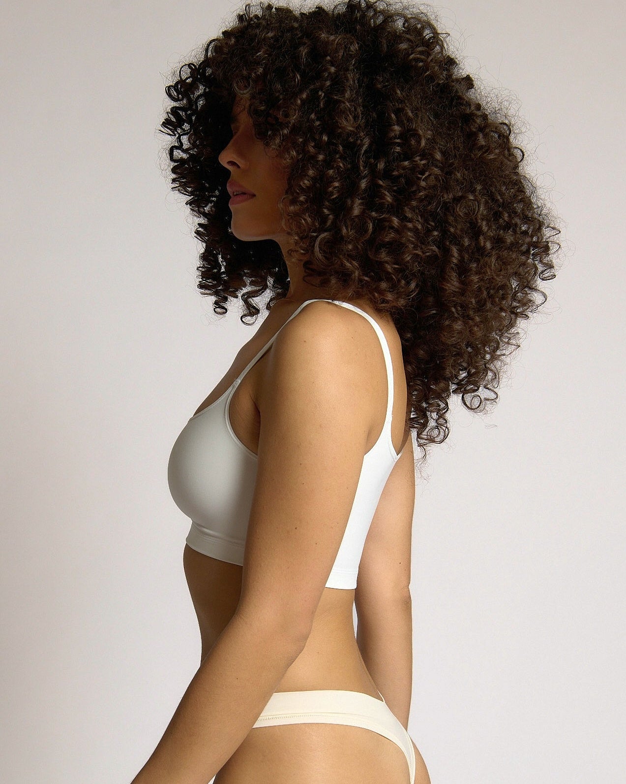 Woman wearing a white cropped cami on a plain background