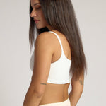 Woman wearing a white cropped cami on a plain background