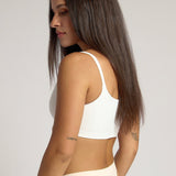 Woman wearing a white cropped cami on a plain background