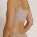 A woman modeling a dusk cropped cami and matching underwear, against a plain light beige studio background.