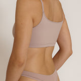 A woman modeling a dusk cropped cami and matching underwear, against a plain light beige studio background.