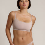 A woman modeling a dusk cropped cami and matching underwear, against a plain light beige studio background.