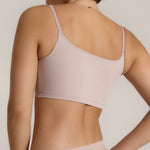 A woman modeling a dusk cropped cami and matching underwear, against a plain light beige studio background.