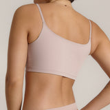 A woman modeling a dusk cropped cami and matching underwear, against a plain light beige studio background.