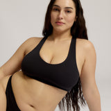 Woman wearing a black racerback on a plain background
