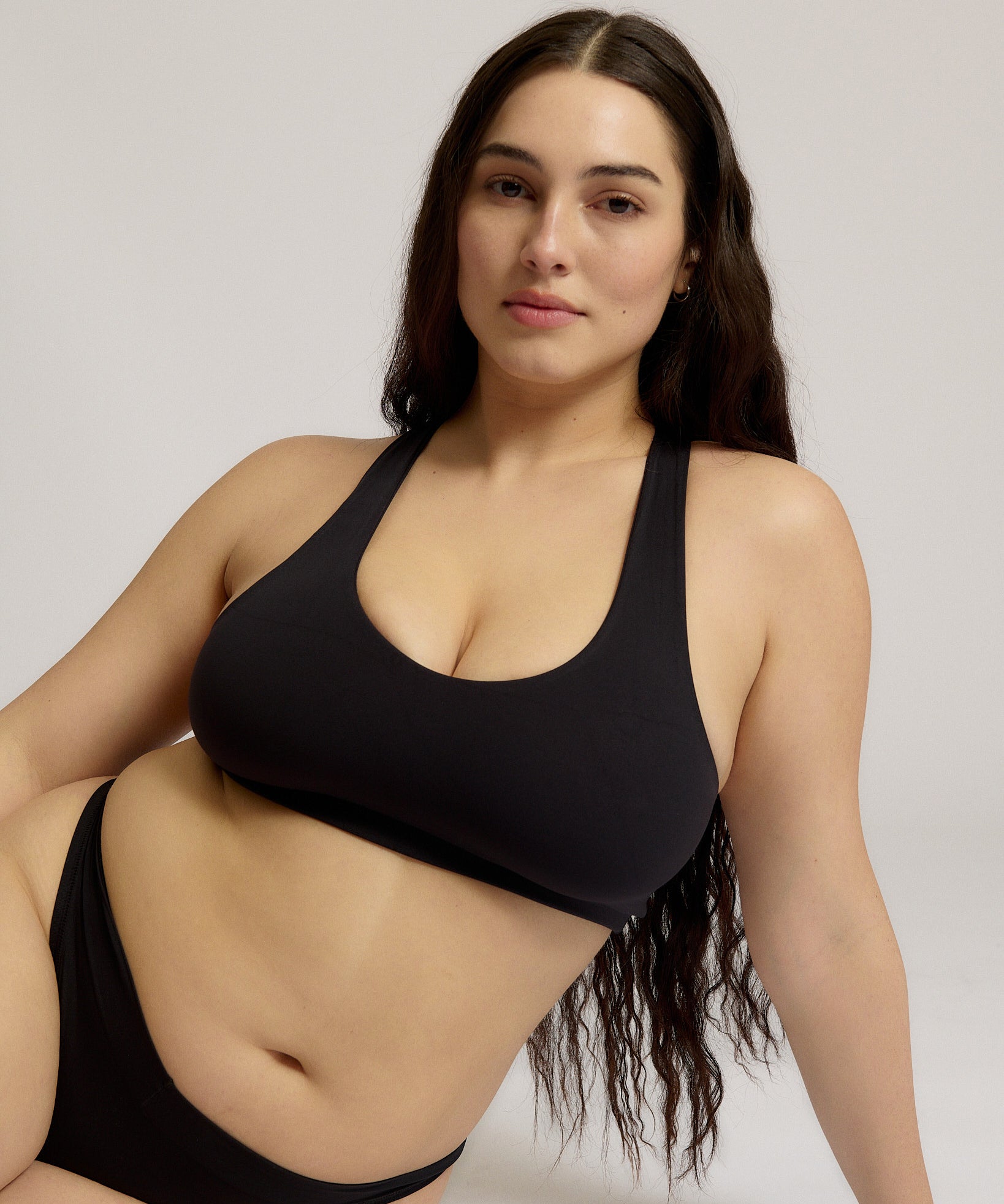 Woman wearing a black racerback on a plain background