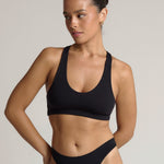 Woman wearing a black racerback on a plain background