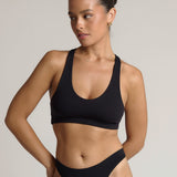 Woman wearing a black racerback on a plain background