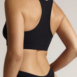 Woman wearing a black racerback on a plain background
