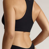 Woman wearing a black racerback on a plain background