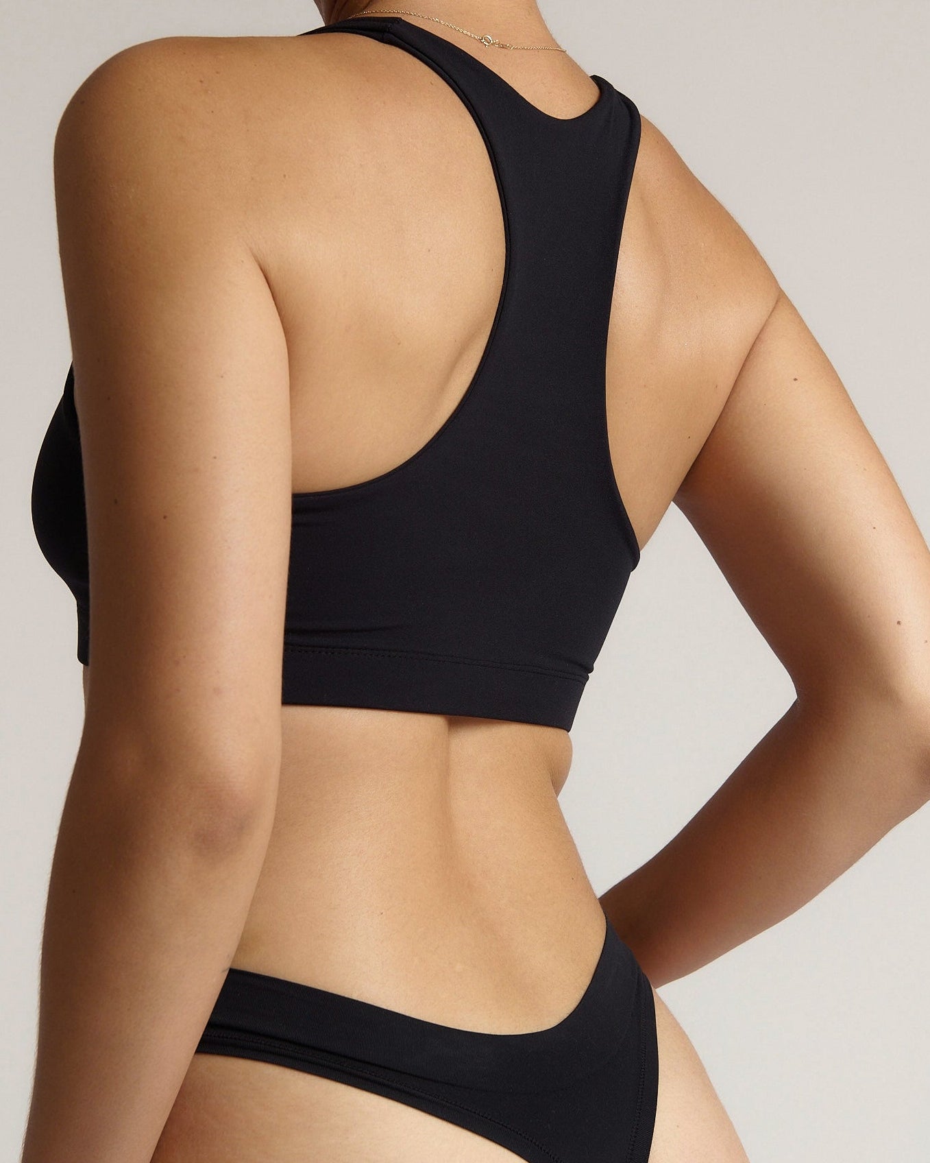 Woman wearing a black racerback on a plain background