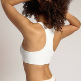 Woman wearing a white racerback on a plain background