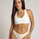 Woman wearing a white racerback on a plain background