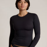 Person wearing a black long-sleeve against a plain background